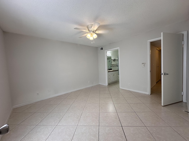 empty room featuring light tile patterned flooring, ceiling fan, and a textured ceiling