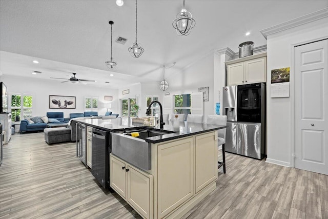 kitchen with sink, stainless steel fridge, dishwasher, a kitchen island with sink, and cream cabinetry