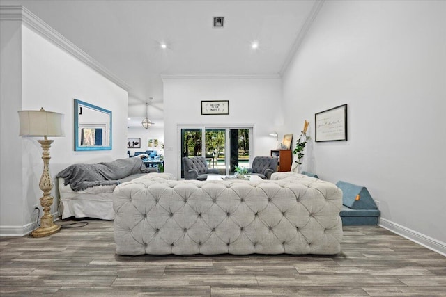 bedroom with hardwood / wood-style flooring, ornamental molding, a towering ceiling, and access to exterior