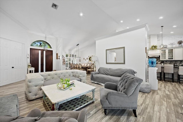 living room featuring crown molding, vaulted ceiling, and light wood-type flooring