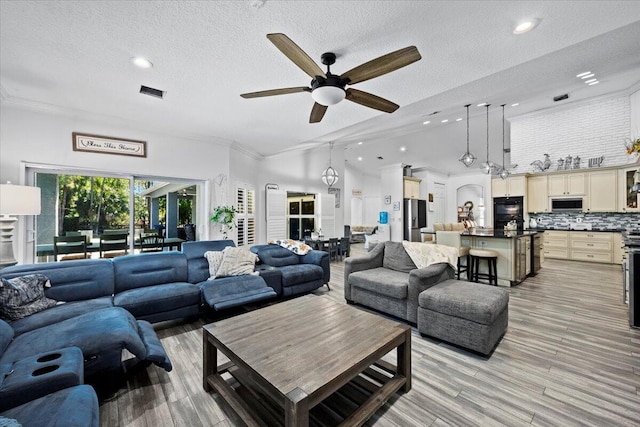 living room featuring ornamental molding, ceiling fan, a textured ceiling, and light hardwood / wood-style floors