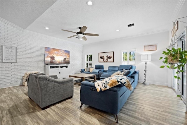 living room featuring crown molding, brick wall, light hardwood / wood-style flooring, and a textured ceiling