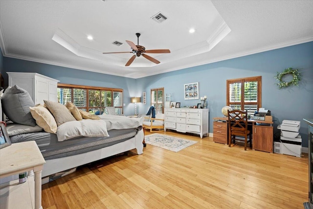 bedroom featuring crown molding, light hardwood / wood-style flooring, ceiling fan, and a tray ceiling