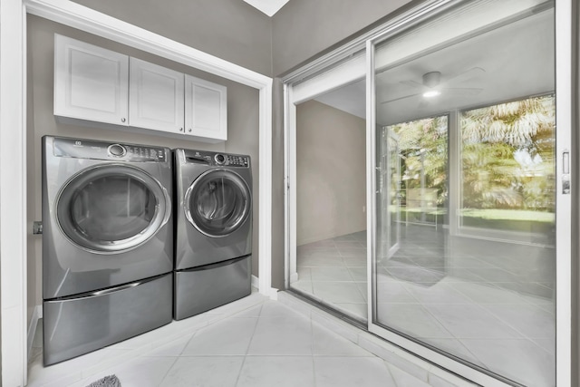 laundry area with washing machine and dryer, light tile patterned floors, and cabinets