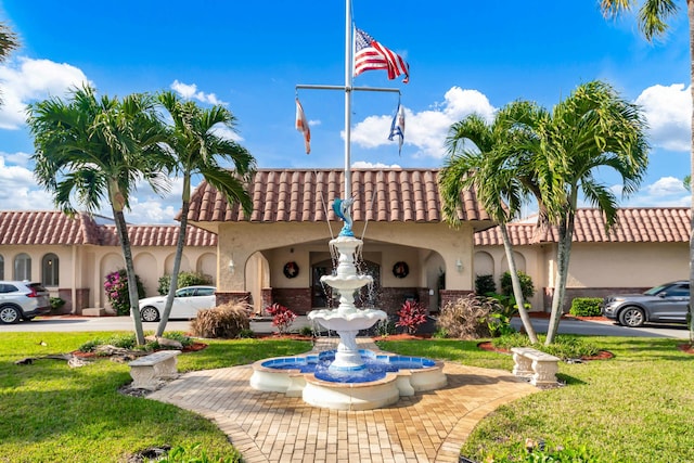 exterior space featuring stucco siding, a front lawn, and a tile roof