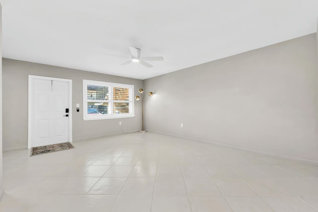 unfurnished room with baseboards, ceiling fan, and light tile patterned flooring