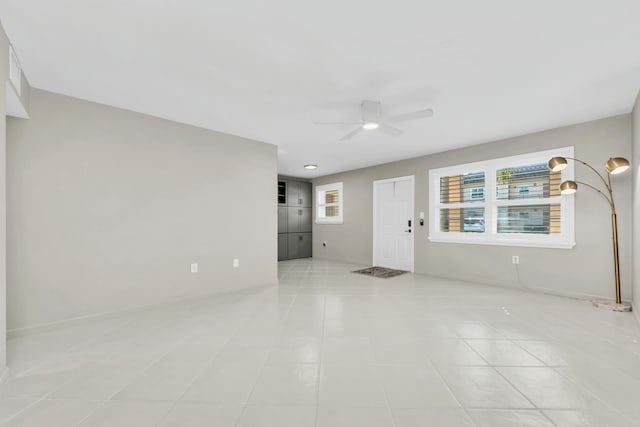 unfurnished room featuring a healthy amount of sunlight, light tile patterned flooring, and a ceiling fan