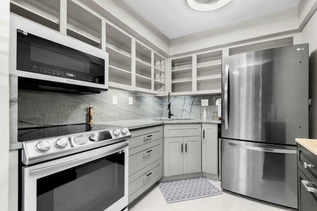 kitchen featuring electric range, a sink, freestanding refrigerator, light tile patterned flooring, and decorative backsplash