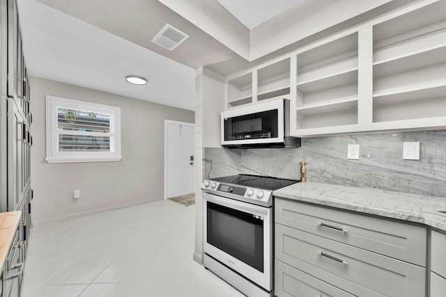 kitchen featuring white microwave, visible vents, light stone countertops, electric range, and tasteful backsplash