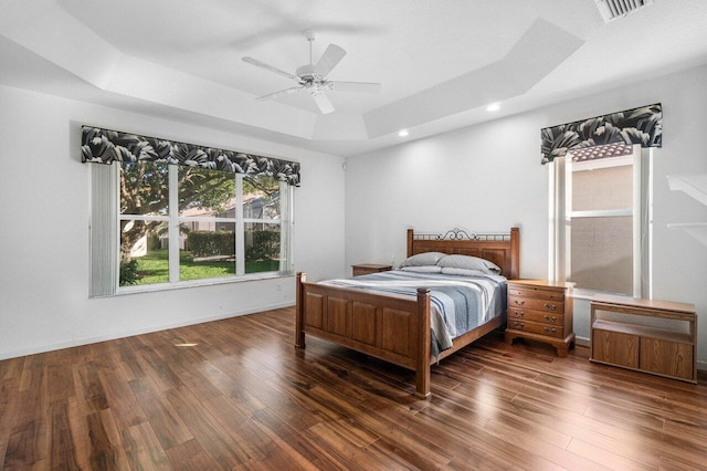 bedroom with a tray ceiling, ceiling fan, and dark hardwood / wood-style flooring