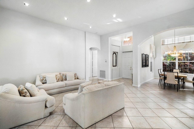 tiled living room with a high ceiling and a chandelier