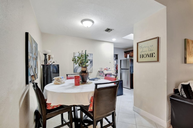 tiled dining space featuring a textured ceiling