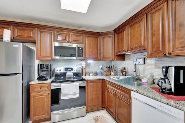 kitchen with light stone countertops, light tile patterned floors, sink, and appliances with stainless steel finishes