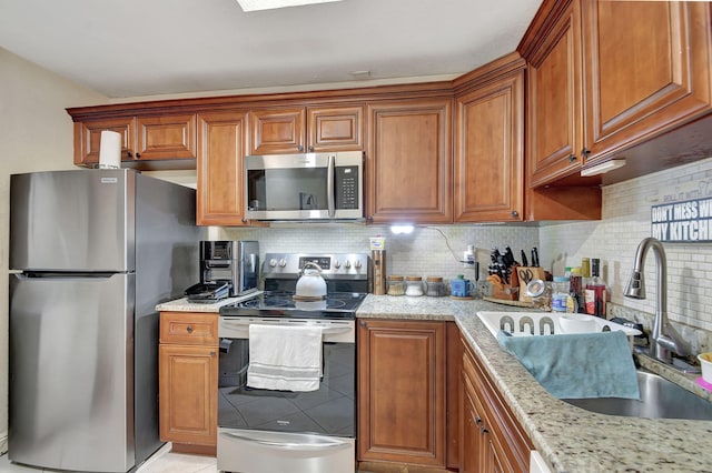 kitchen with light stone countertops, sink, decorative backsplash, light tile patterned flooring, and appliances with stainless steel finishes