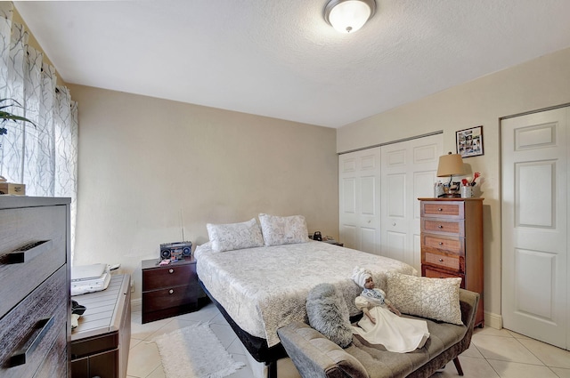 bedroom featuring light tile patterned floors, a textured ceiling, and a closet