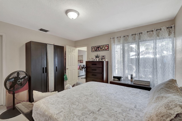 bedroom with a textured ceiling and tile patterned floors