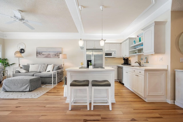 kitchen featuring a sink, open floor plan, appliances with stainless steel finishes, light wood-type flooring, and open shelves