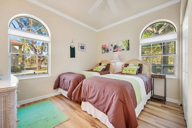 bedroom with crown molding, multiple windows, baseboards, and wood finished floors