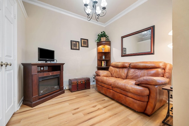 living room featuring a glass covered fireplace, a notable chandelier, crown molding, and wood finished floors