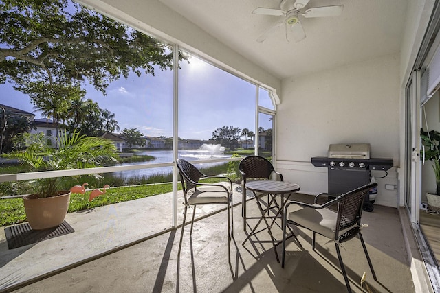 sunroom with ceiling fan and a water view