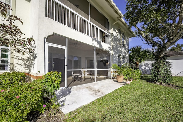 view of yard featuring a sunroom, a patio, and a balcony