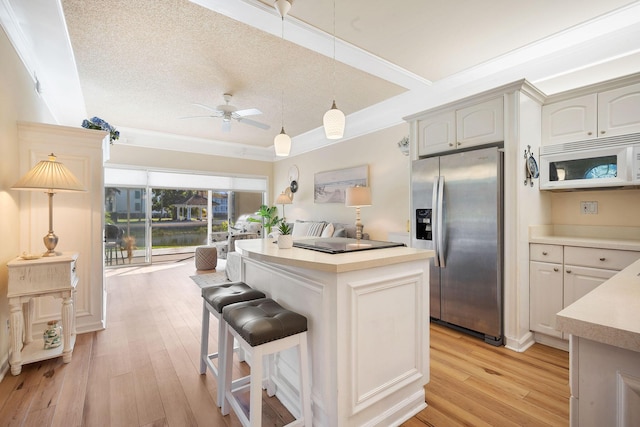 kitchen with stainless steel refrigerator with ice dispenser, white cabinets, a center island, and crown molding