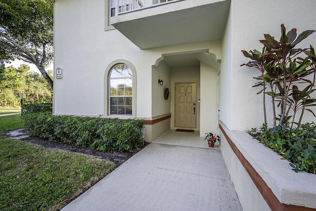 entrance to property featuring a balcony and stucco siding