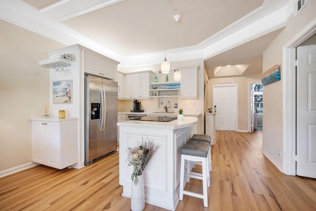 kitchen with a center island, light wood finished floors, open shelves, light countertops, and stainless steel fridge