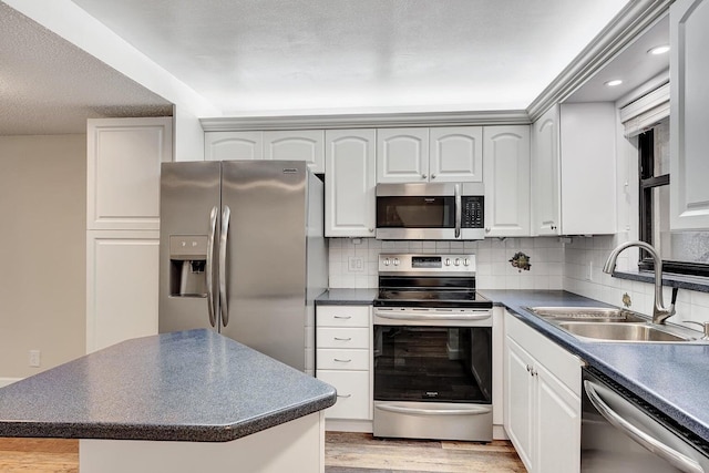 kitchen featuring sink, stainless steel appliances, a kitchen island, decorative backsplash, and white cabinets