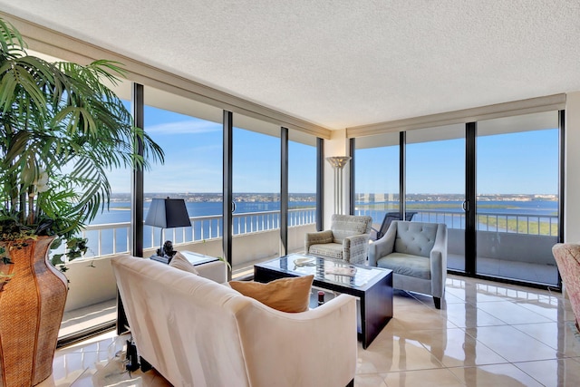 tiled living room with a water view, a wall of windows, and a textured ceiling