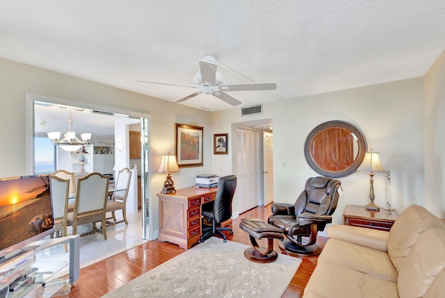 office space featuring hardwood / wood-style floors, ceiling fan with notable chandelier, and a textured ceiling