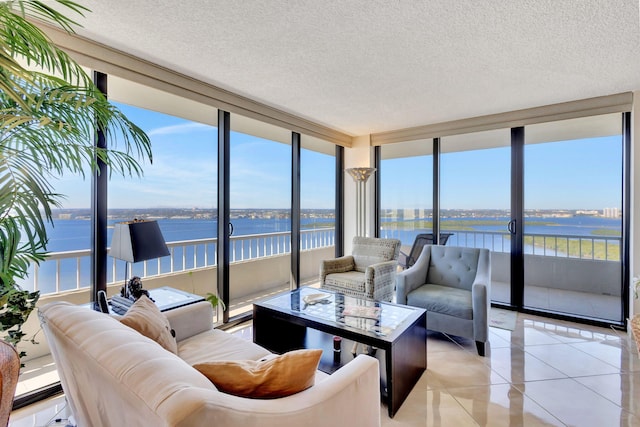 living room featuring a textured ceiling, a water view, light tile patterned floors, and a wall of windows