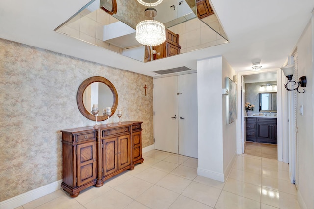 corridor featuring sink, light tile patterned floors, and a chandelier