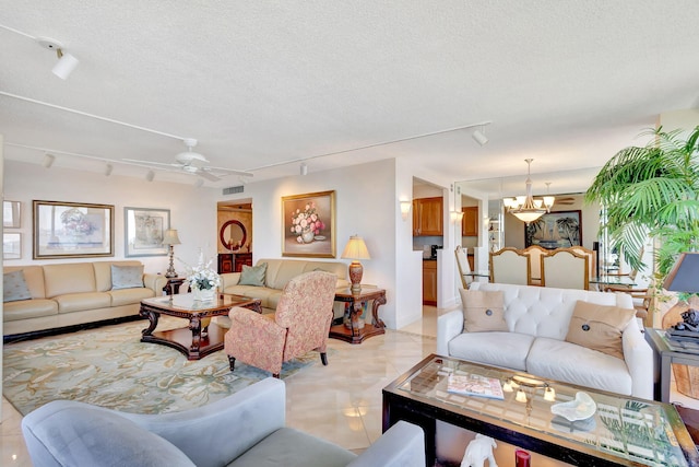 living room featuring a textured ceiling, light tile patterned floors, rail lighting, and ceiling fan with notable chandelier