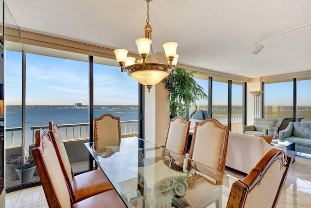 dining room with light tile patterned floors, a water view, a chandelier, and a textured ceiling