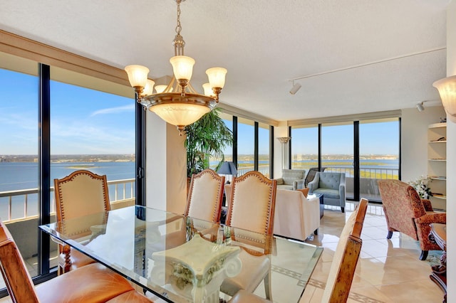 tiled dining room featuring plenty of natural light, a water view, and a chandelier