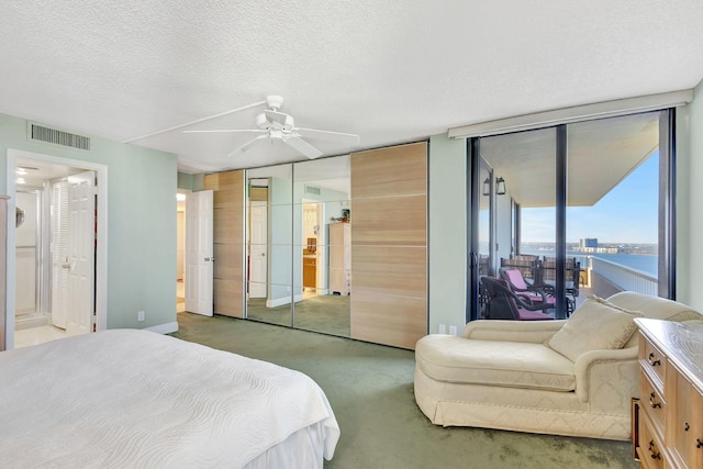 bedroom with access to exterior, a textured ceiling, ceiling fan, a water view, and carpet floors