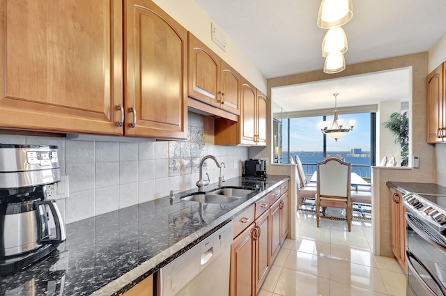 kitchen with appliances with stainless steel finishes, sink, pendant lighting, a water view, and a notable chandelier