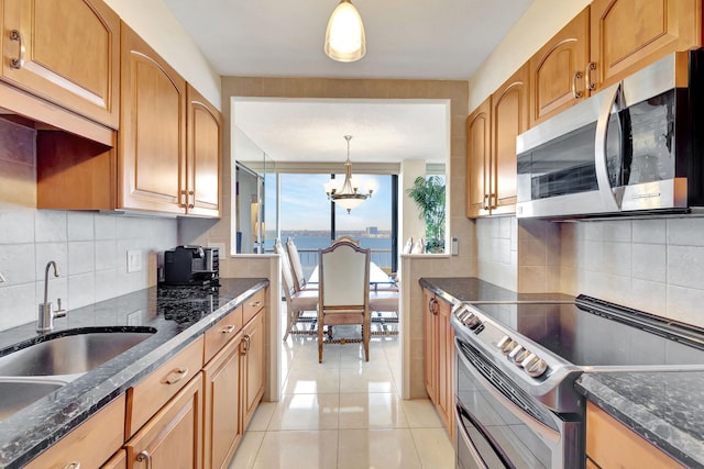 kitchen featuring stainless steel appliances, sink, decorative light fixtures, an inviting chandelier, and a water view