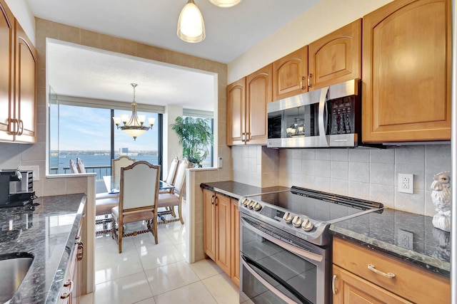 kitchen with plenty of natural light, a water view, light tile patterned floors, and stainless steel appliances