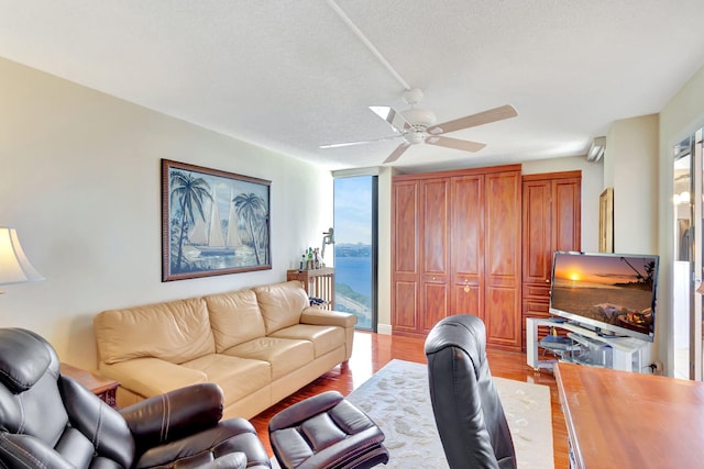 living room with a textured ceiling, light hardwood / wood-style floors, and ceiling fan