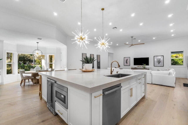 kitchen with appliances with stainless steel finishes, pendant lighting, sink, white cabinets, and a large island