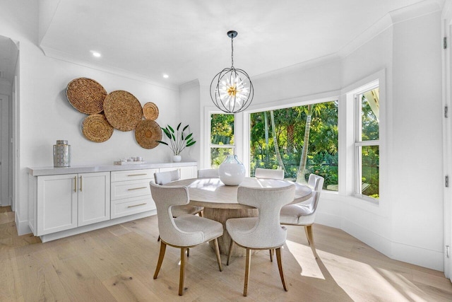 dining area with an inviting chandelier, crown molding, and light wood-type flooring