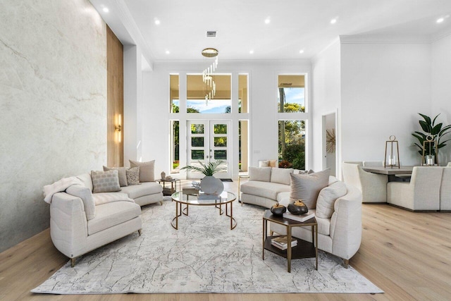 living room featuring crown molding, light hardwood / wood-style flooring, and a high ceiling