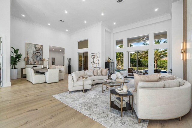 living room featuring crown molding, ceiling fan with notable chandelier, and light hardwood / wood-style floors