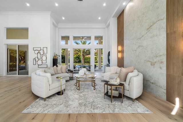 living room with crown molding, light hardwood / wood-style flooring, and a high ceiling