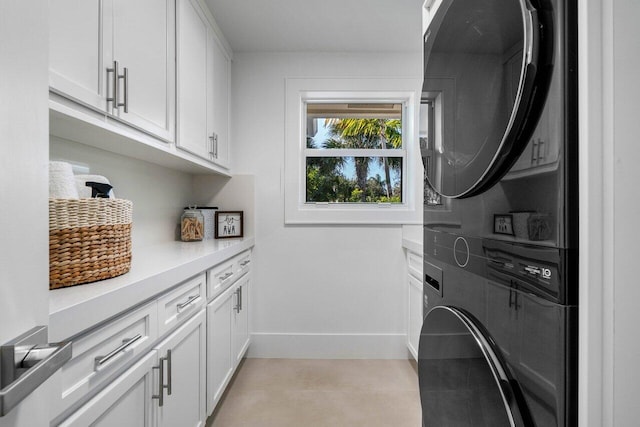 laundry room with stacked washer / dryer and cabinets