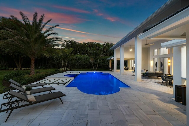 pool at dusk featuring an outdoor hangout area, a patio area, ceiling fan, and an in ground hot tub