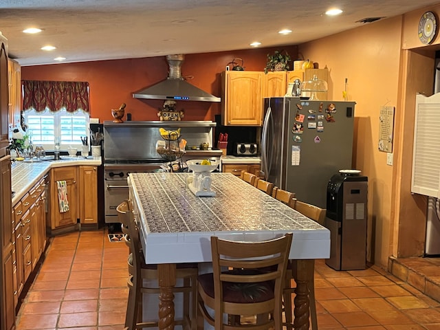 kitchen with a kitchen island, light tile patterned floors, exhaust hood, and tile counters