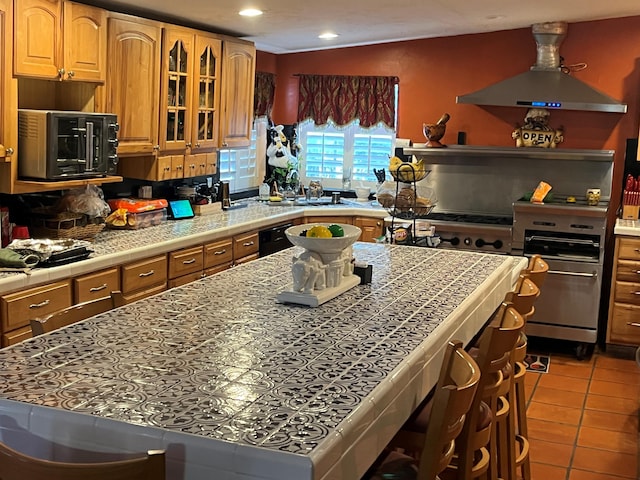 kitchen with light tile patterned floors, tile counters, black appliances, and island exhaust hood